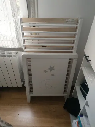 Cuna de bebé blanca con colchón.