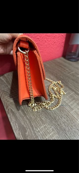 Bolso naranja con cadena dorada y flor