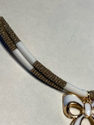 Collana a righe bianco e oro con ciondolo fiocco