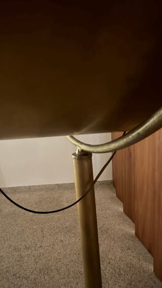 Lámpara de pie dorada estilo foco.
