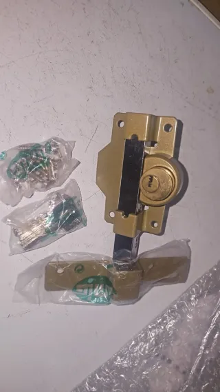 Cerradura dorada con llave y tornillos