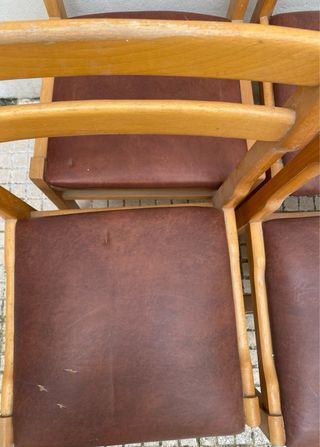 Sillas de madera con asiento polipiel marrón.