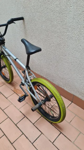 Bicicleta BMX plateada con ruedas verdes