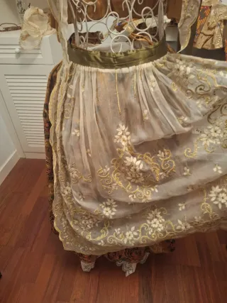 Con delantal y manteleta bordado en oro