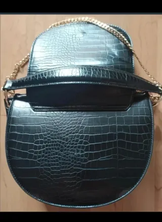 Bolso negro efecto cocodrilo con cadena dorada.