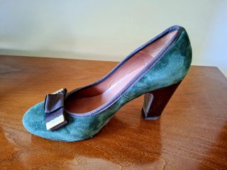 Zapatos de tacón verdes con lazo marrón.