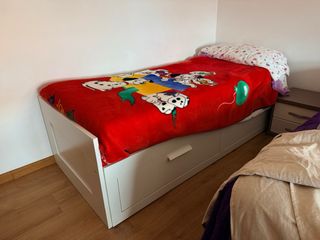 Cama individual blanca con colchón.