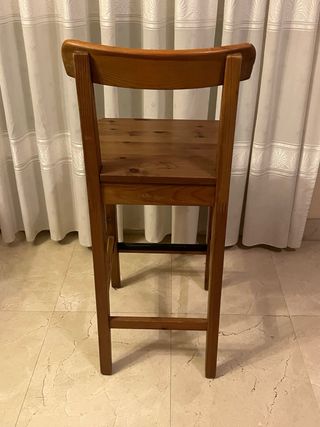 Silla alta de madera oscura, rústica.