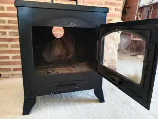 Estufa de leña negra con puerta de cristal