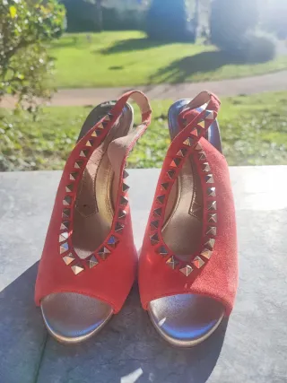 Zapatos de tacón rojos con tachuelas doradas