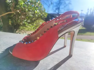 Zapatos de tacón rojos con tachuelas doradas