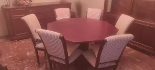 Mesa octogonal de madera con sillas tapizadas.