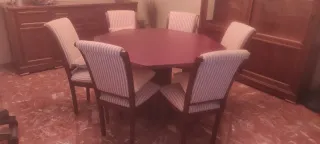 Mesa octogonal de madera con sillas tapizadas.