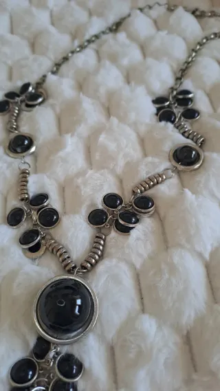 Collar largo plateado con bolas negras.