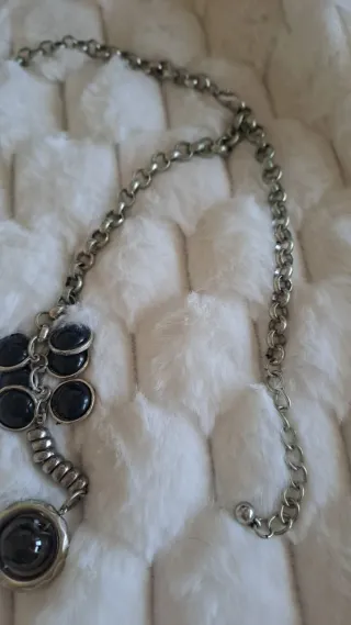 Collar largo plateado con bolas negras.
