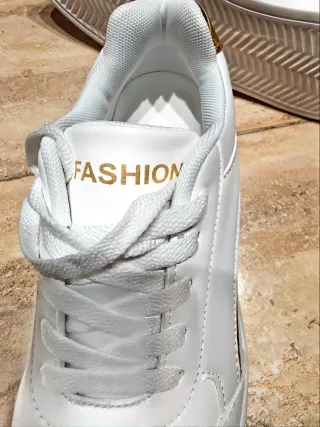 Zapatillas Fashion blancas con detalle dorado.