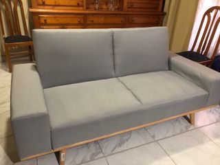 Sofá gris de tela con patas de madera
