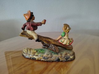 Figura de porcelana de dos niños en balancín