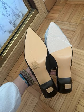 Tacones negros con detalle dorado.