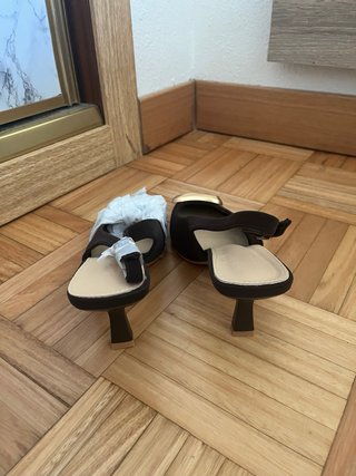 Tacones negros con detalle dorado.