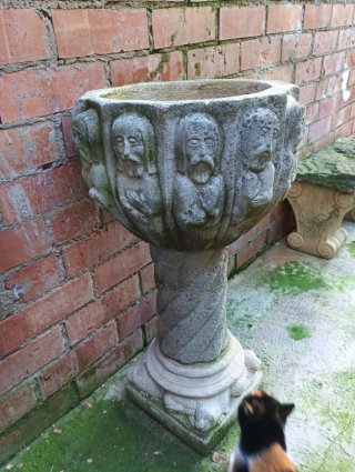 Jardinera antigua de piedra con caras