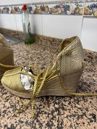 Sandalias doradas Corina cuña atadas al tobillo.