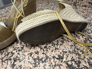 Sandalias doradas Corina cuña atadas al tobillo.