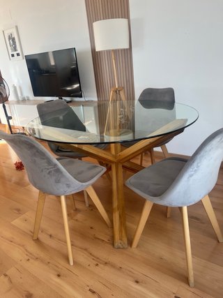 Mesa redonda de cristal y patas de madera.