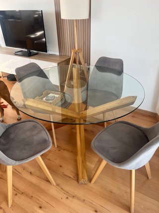 Mesa redonda de cristal y patas de madera.
