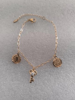 Pulsera dorada con llave y monedas