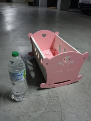 Cuna de madera rosa y blanca para muñecas.