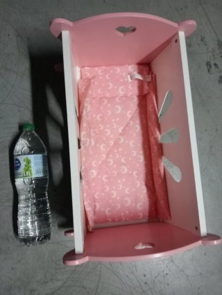 Cuna de madera rosa y blanca para muñecas.