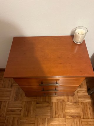 Mesita de noche de madera con tiradores dorados.