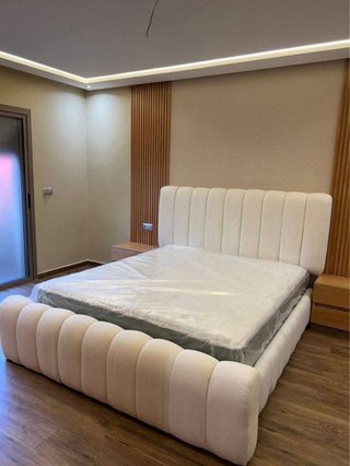 Cama tapizada beige con cabecero capitoné