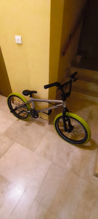 Bicicleta BMX plateada con ruedas verdes