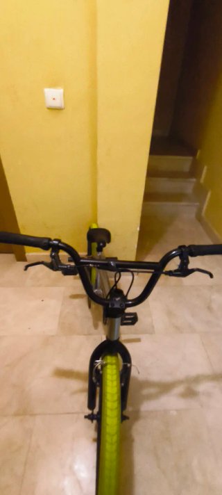 Bicicleta BMX plateada con ruedas verdes