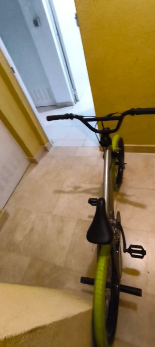 Bicicleta BMX plateada con ruedas verdes