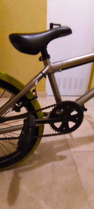 Bicicleta BMX plateada con ruedas verdes