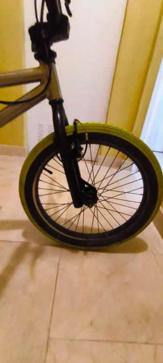 Bicicleta BMX plateada con ruedas verdes