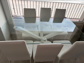 Mesa de cristal con 8 sillas blancas,