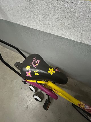 Bicicleta infantil amarilla con ruedines y palo