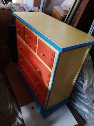 Cómoda de madera colorida con 7 cajones.