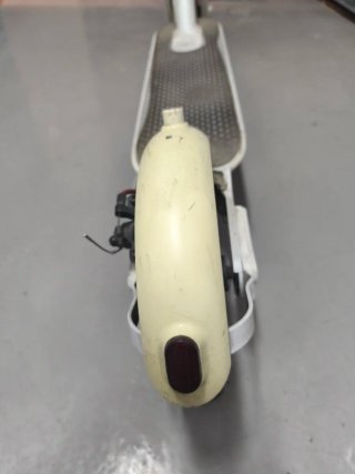 Patinete eléctrico blanco, tiene el cargador.