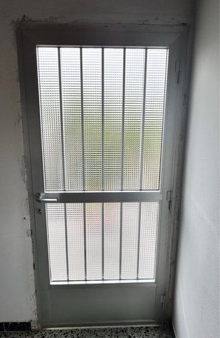 Puerta de aluminio con reja y cristal