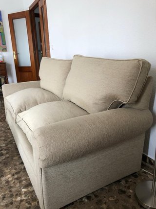 Sofá de tela beige con relleno de plumas