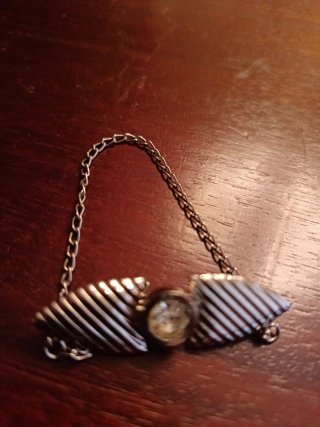 Broche plateado con cadena y piedra