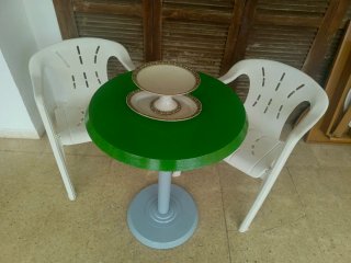 Mesa redonda verde con 2 sillas blancas