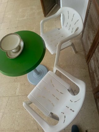 Mesa redonda verde con 2 sillas blancas