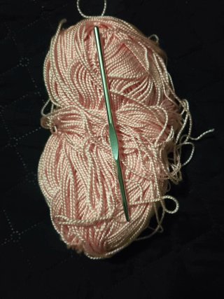 Hilo rosa y aguja de ganchillo