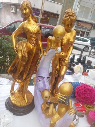 Figuras doradas de mujer y alienígenas